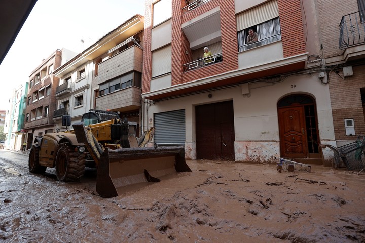 Una máquina escavadora retira el lodo acumulado en las calles. Foto: EFE