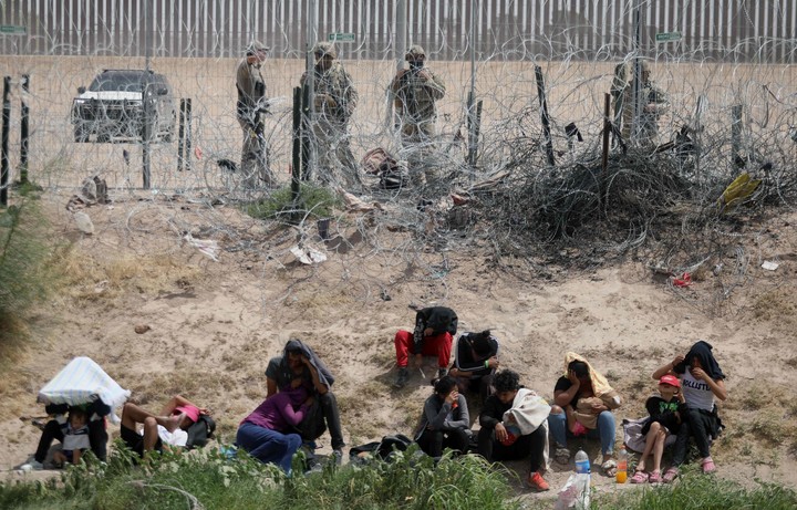 La Guardia Nacional de Texas custodia a un grupo de migrantes que intenta cruzar la valla desde México, en una imagen de junio. Foto: AFP  