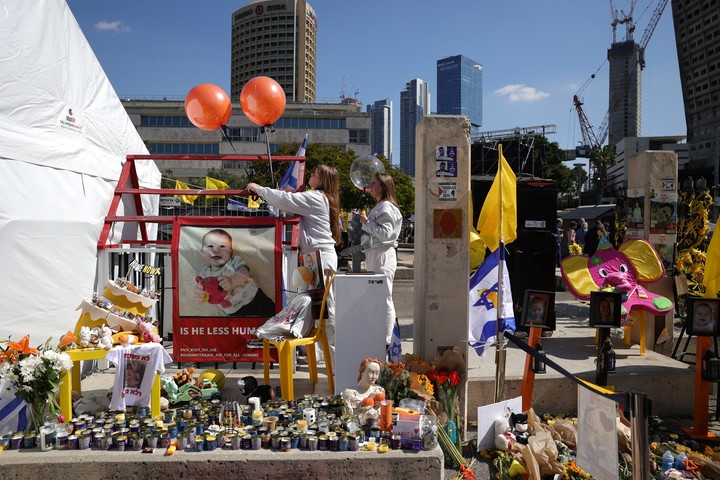 Una foto del pequeño Kfir y unos globos naranjas, en el homenaje a la familia Bibas. Foto EFE