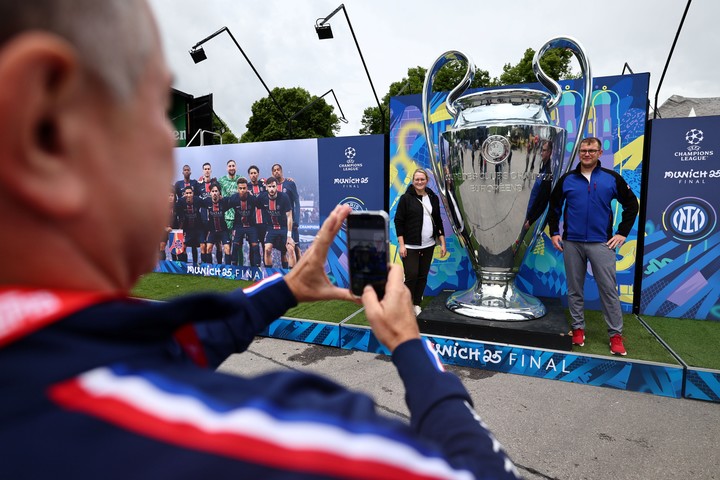 Hinchas posan en Munich junto a una replica de la copa de la Champions League. Foto: EFE