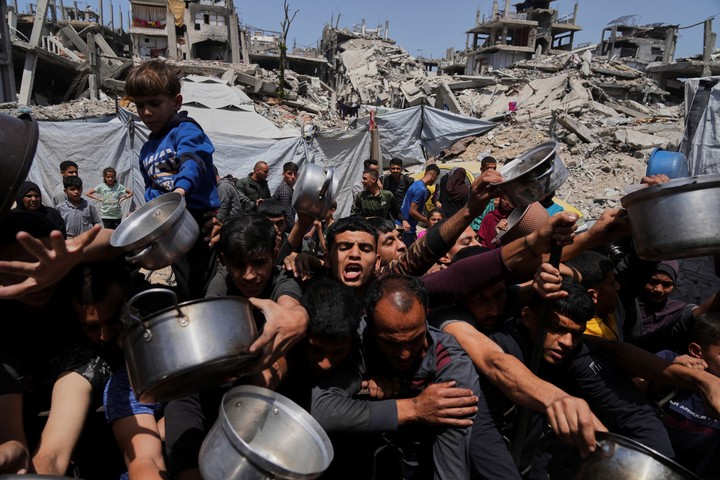 Palestinos luchan por conseguir alimentos donados en un comedor comunitario en Beit Lahia, al norte de la Franja de Gaza. Foto AP