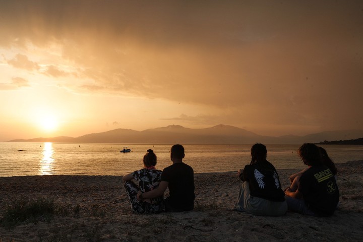 Un grupo de jóvenes corsos contempla el atardecer sobre Ajaccio desde la playa de Agosta, en Albitreccia, en la isla mediterránea francesa de Córcega. Foto AFP