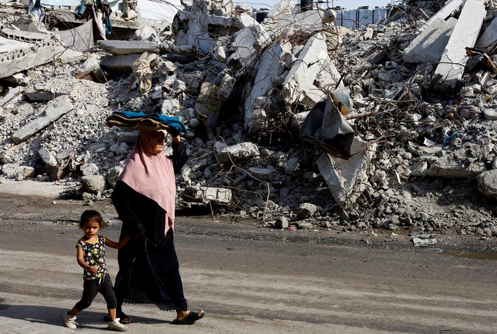 Palestinos pasan junto a un edificio residencial destruido en Gaza.  Foto REUTERS/Mahmoud Issa