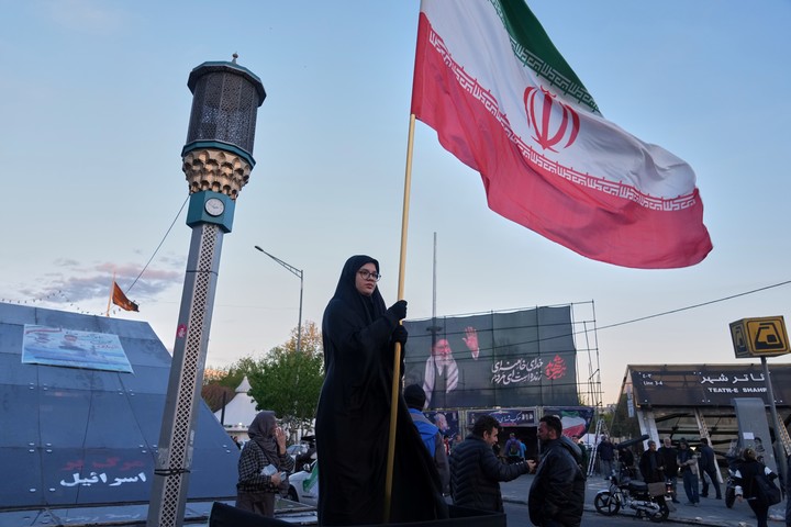 Una mujer sostiene una bandera iraní en una intersección en el centro de Teherán, Irán. Foto AP