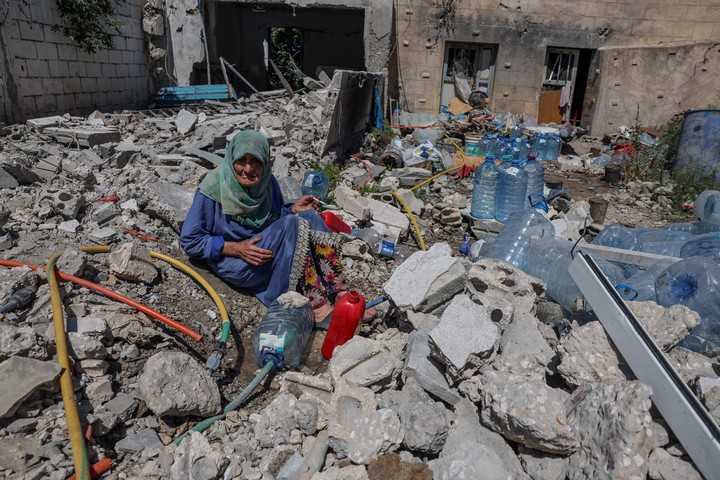 Una mujer carga agua entre las ruinas de una casa en Tiro, Líbano. Foto: Reuters