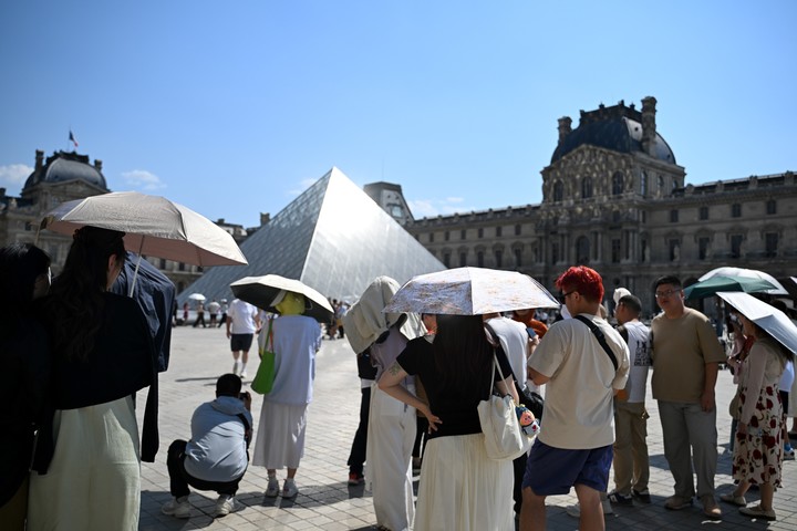 Turistas usan paraguas para protegerse del sol en París. Foto: AP