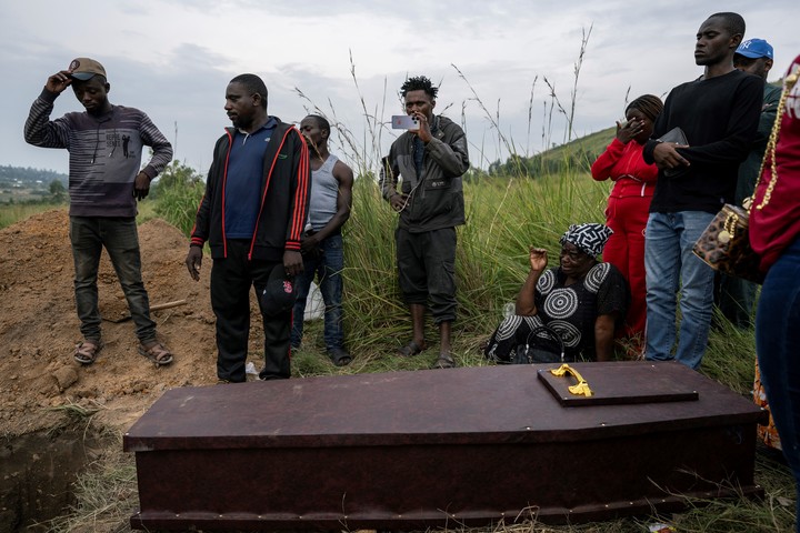 Thierry Mumbere, un amigo, el segundo por la izquierda, junto a familiares que asistían al funeral del señor Okito.  Fotos de Arlette Bashizi para The New York Times.